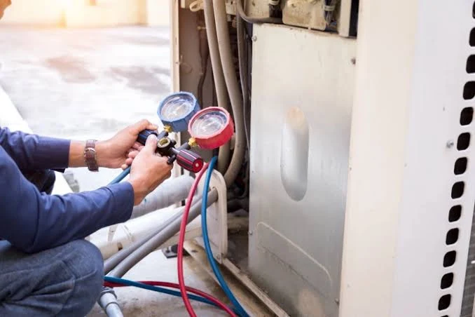 Technician checking refrigerant pressure with HVAC service gauges