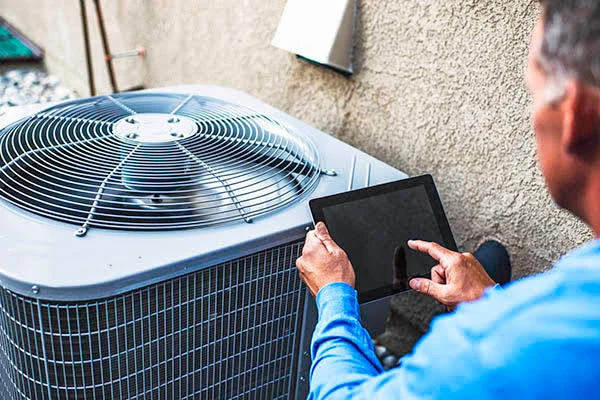 Technician inspecting a residential condenser with a tablet